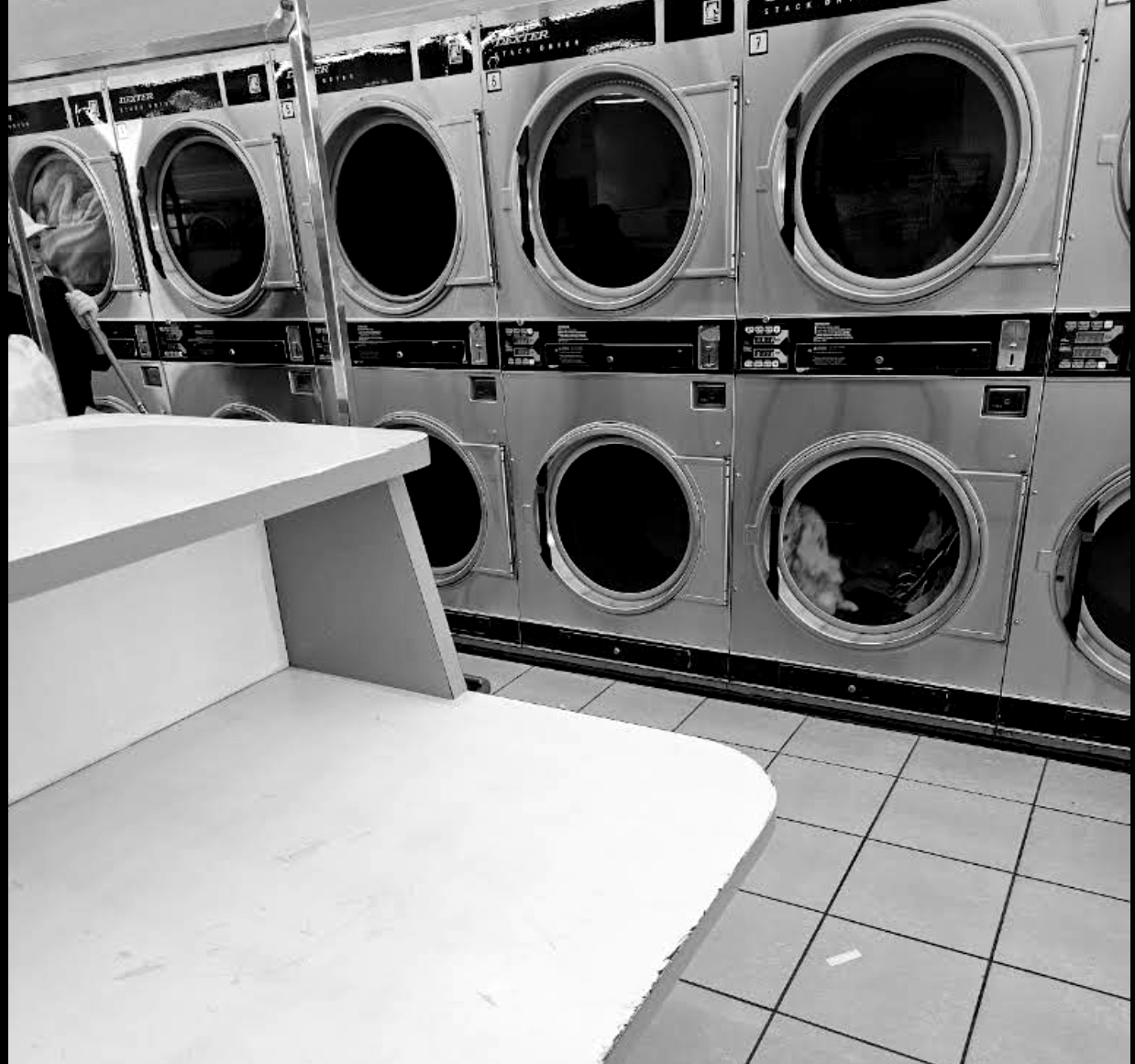 The folding table and stacked dryers at Ball Lemon Coin Laundry, with Maria on the floor behind